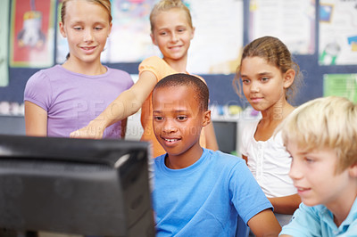 Buy stock photo A group of young school kids sitting and standing around a computer during class