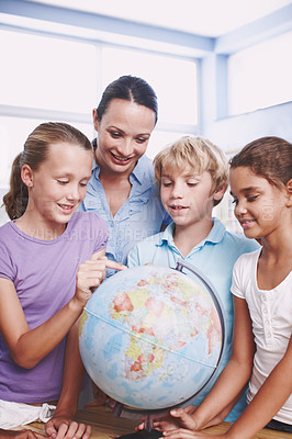 Buy stock photo A group of schoolchildren learning about the world with their geography teacher