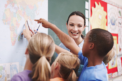 Buy stock photo An excited class pointing at a world map with their geography teacher