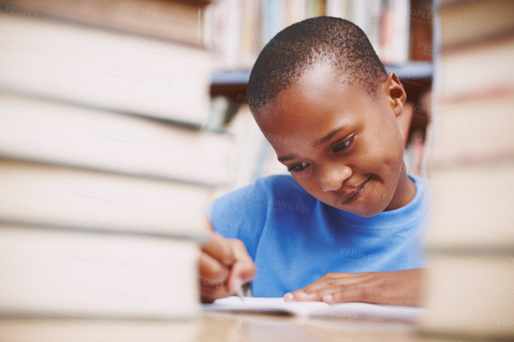 Buy stock photo Black child, writing and education with books in library for assessment research, learning notes and studying. Boy student, notebook and school test, language development and reading work for exam