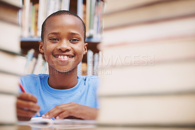 Buy stock photo An african american boy surrounded by books at the library