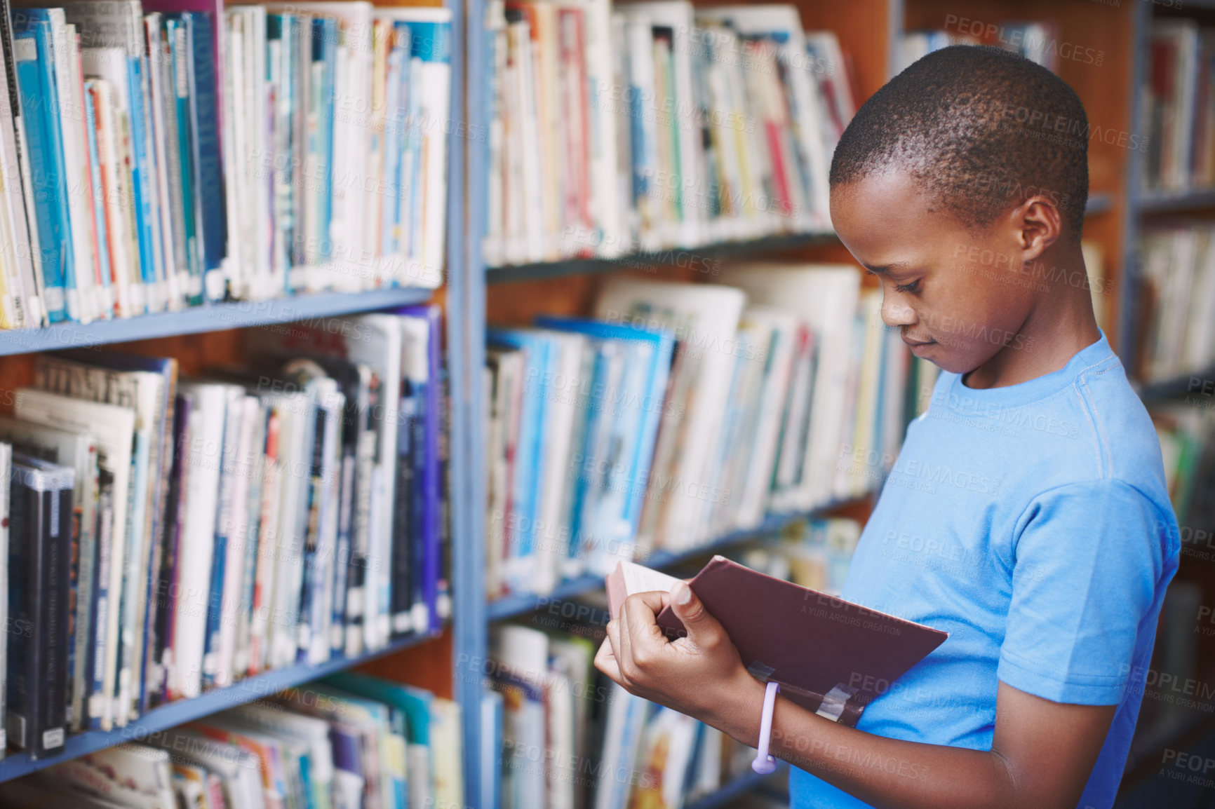 Buy stock photo Black boy, library and serious for reading book at elementary school for literacy, knowledge and information. Student, kid and concentrate with fairytale, novel and literature for brain development