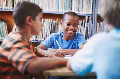 Buy stock photo An african american boy sitting in the library and working with his classmates