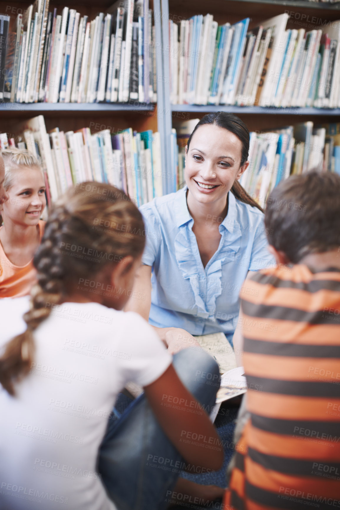 Buy stock photo Teacher, kids and smile at library with storytelling for education, knowledge and literacy. People, educator and happy with students at elementary school with reading book for brain development