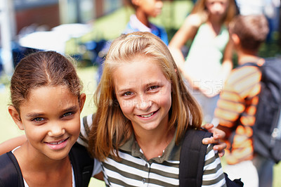 Buy stock photo Two schoolgirl friends standing next to each other smiling up at the camera - copyspace