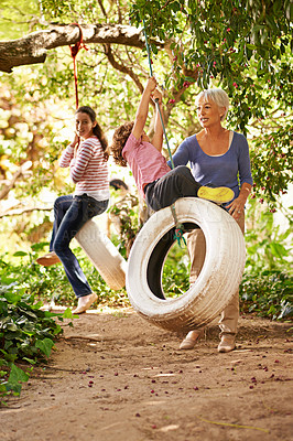 Buy stock photo Grandmother, garden and grandkids playing with senior woman on tyre swing or holiday and having fun in summer. Excited, grandchildren and outdoors on jungle gym together or on sunny weekend at a park