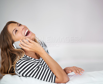 Buy stock photo Shot of a young woman laughing while talking on the phone at home