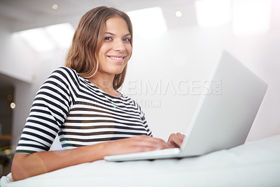 Buy stock photo Portrait of a young woman using a laptop while sitting on a sofa at home