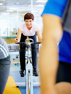Buy stock photo Beautiful woman on a stationary bike at the gym