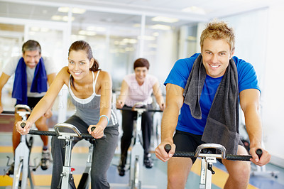 Buy stock photo Group of people using exercise bikes at the gym