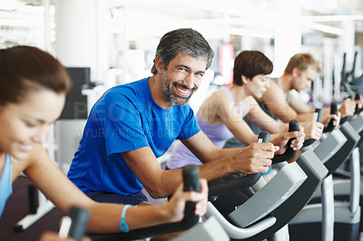 Buy stock photo Cropped shot of a row of people working out on the exercise bikes at the gym