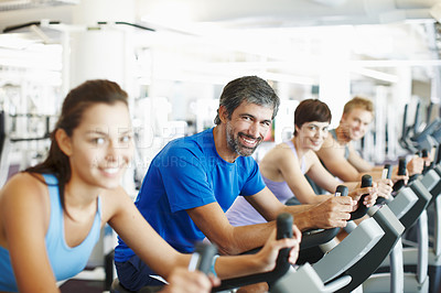 Buy stock photo Cropped shot of a row of people working out on the exercise bikes at the gym