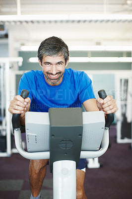 Buy stock photo Cropped portrait of a handsome man using an exercise bike in the gym