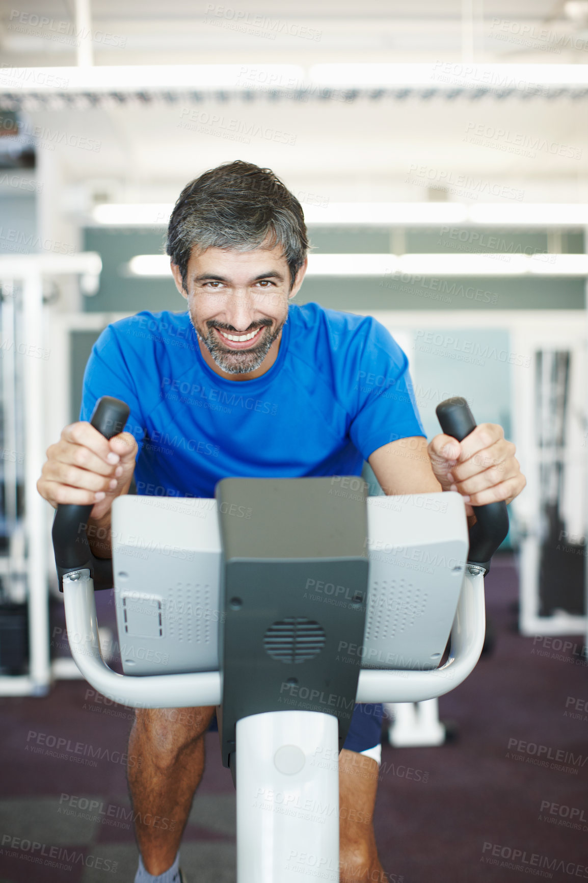 Buy stock photo Cropped portrait of a handsome man using an exercise bike in the gym