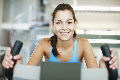 Buy stock photo Cropped portrait of an attractive young woman using an exercise bike in the gym