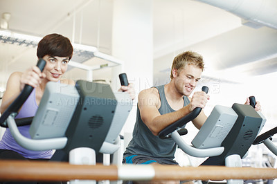 Buy stock photo Cropped shot of two people using the exercise bikes in the gym