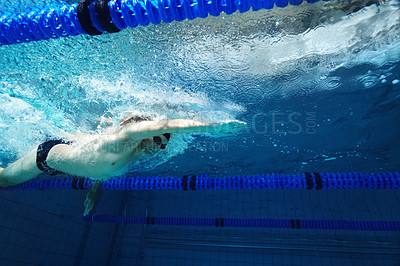 Buy stock photo A young male competitor swimming freestyle in a pool