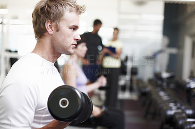 Buy stock photo Cropped shot of a handsome young man working out with weights in the gym