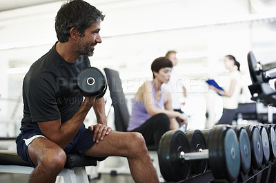 Buy stock photo Cropped shot of a handsome man working out with weights in the gym
