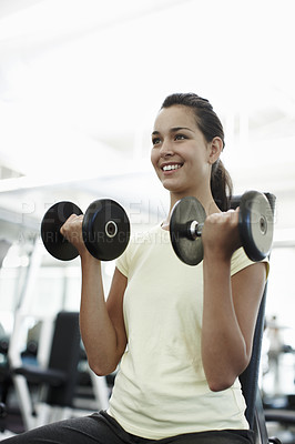 Buy stock photo Cropped shot of an attractive young woman using dumbbells in the gym