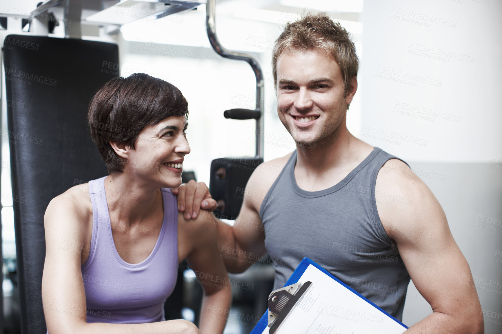 Buy stock photo Personal trainer, man and woman in portrait with clipboard, smile or progress for weightlifting at gym. People, man and coach with checklist for happy, help or exercise with notes at club in Greece