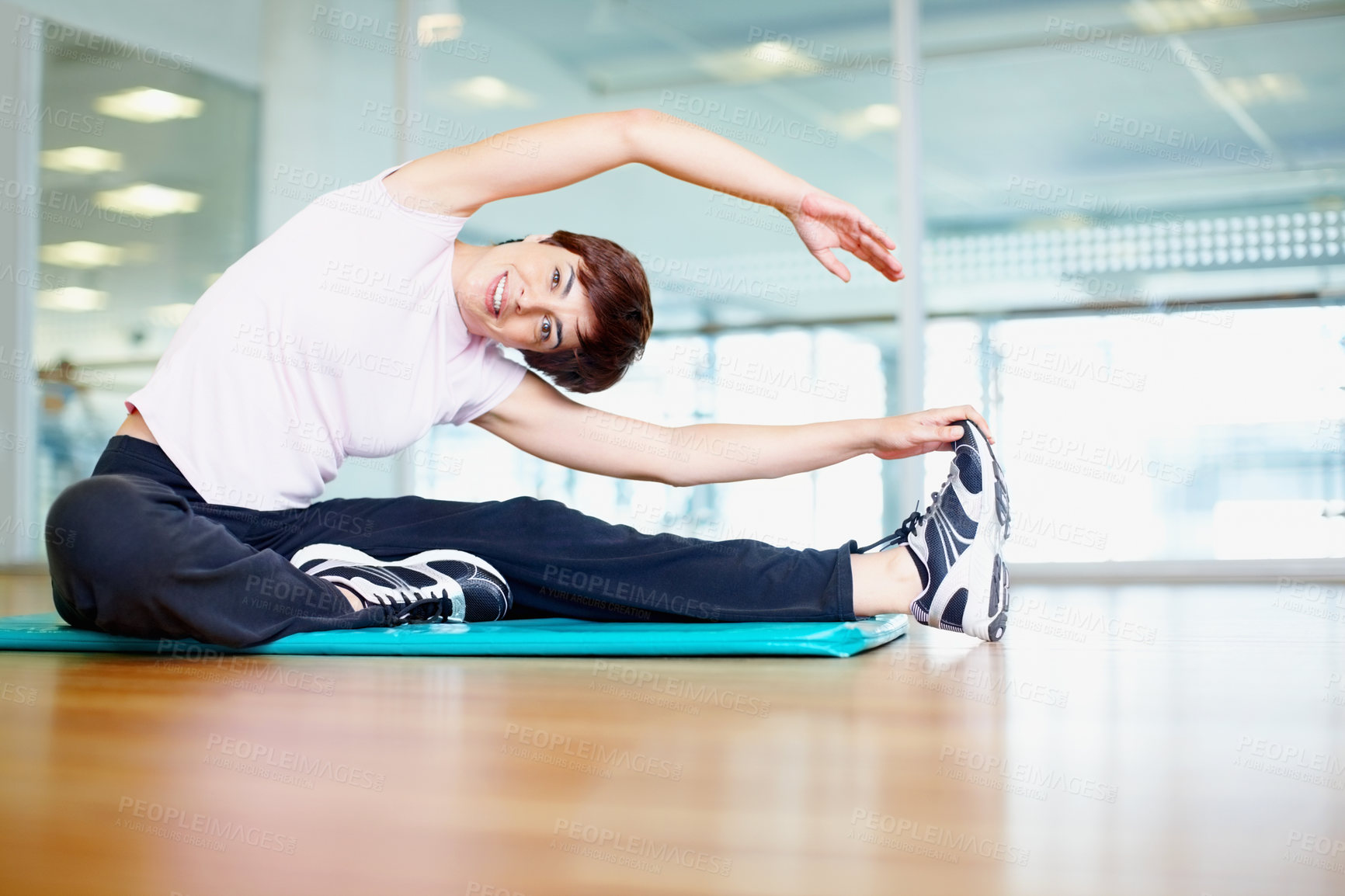 Buy stock photo Portrait of smiling woman doing a stretching exercise in gym
