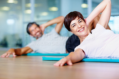 Buy stock photo Beautiful woman exercising on yoga mat with man in background