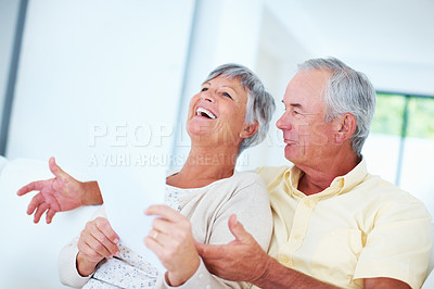 Buy stock photo Cheerful mature couple smiling while discussing domestic bills
