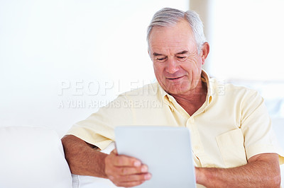 Buy stock photo Handsome mature man using tablet PC while sitting on couch