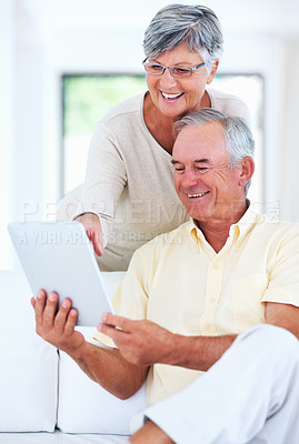 Buy stock photo Senior couple, tablet and home for video, surfing social media and internet for communication. Elderly people, relax and together for bonding in living room, reading funny ebook and streaming comic