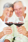 Smiling mature couple toasting with red wine