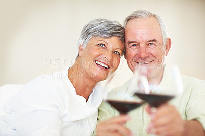 Buy stock photo Portrait of happy mature couple holding wine glasses while sitting on couch