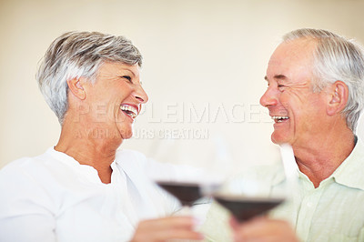 Buy stock photo Cheerful mature couple enjoying time together at home toasting red wine