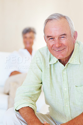 Buy stock photo Portrait of happy mature man smiling at home with woman in background