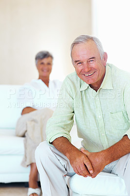 Buy stock photo Portrait of happy mature man smiling in living room with woman in background