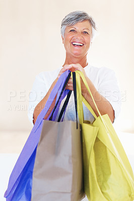Buy stock photo Portrait of happy mature woman standing while carrying shopping bags