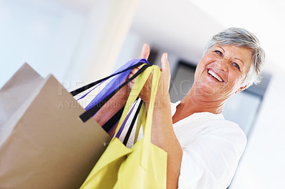 Buy stock photo Portrait of happy mature woman standing while carrying shopping bags