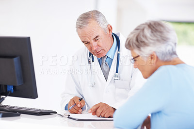 Buy stock photo Confident doctor discussing medical report with mature patient