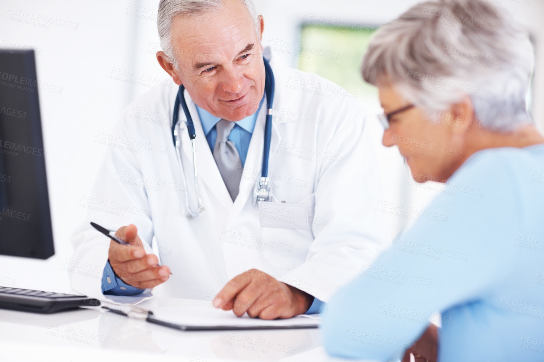 Buy stock photo Smiling male doctor discussing medical report with mature female