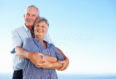Buy stock photo Portrait of happy mature couple smiling together against blue sky