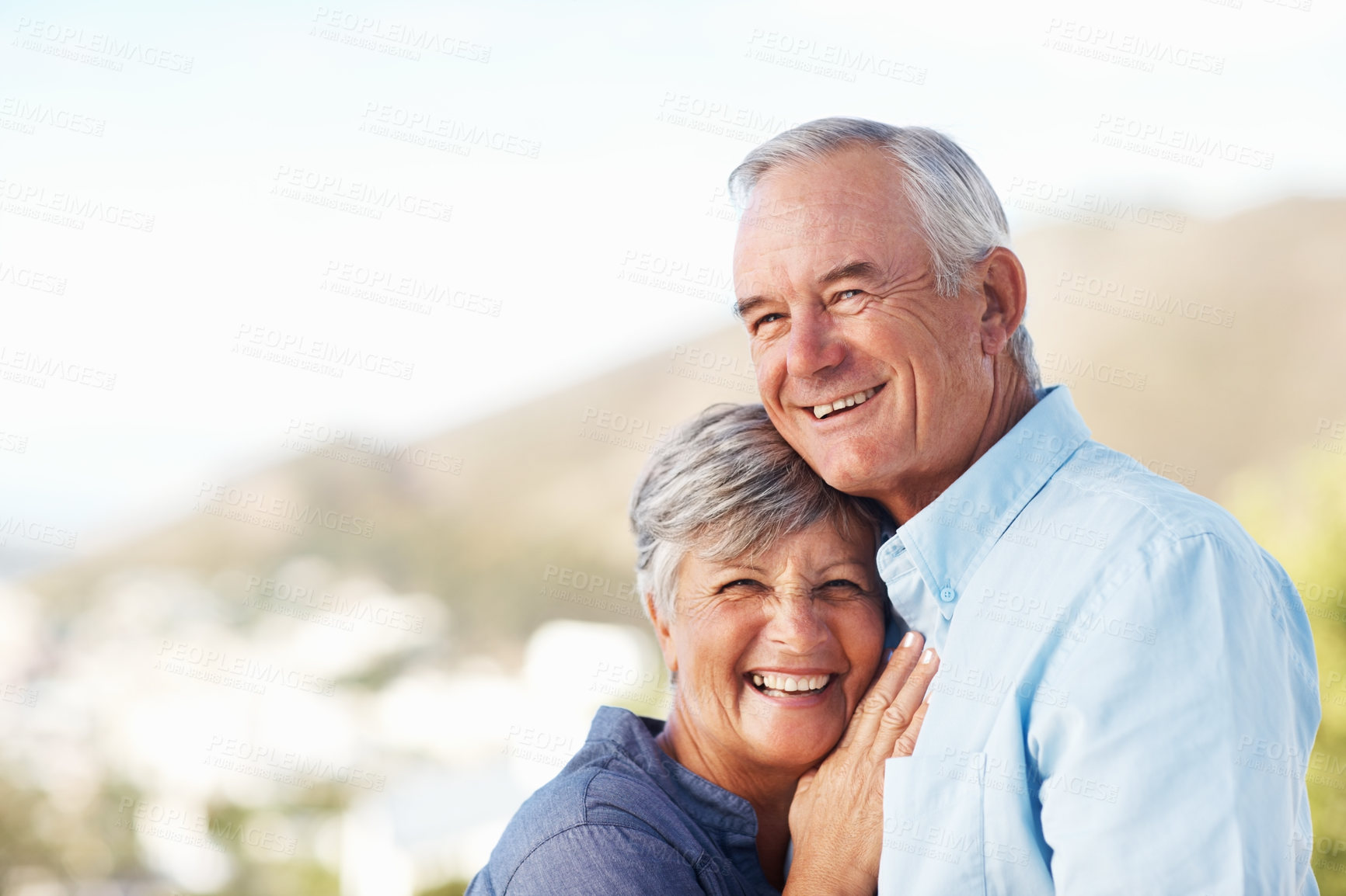 Buy stock photo Portrait of smiling mature woman leaning on man's chest with mountain in background