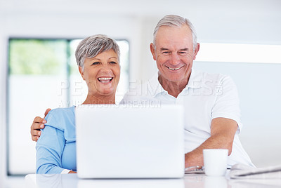 Buy stock photo Happy mature couple smiling while using laptop at home