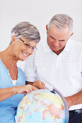 Buy stock photo Happy mature couple planning vacation while looking at globe