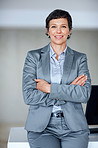 Confident mature woman leaning against desk