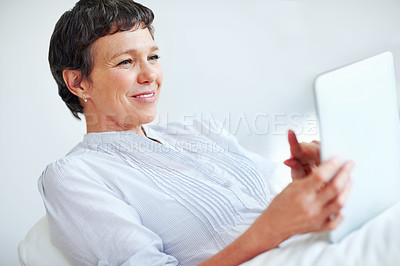 Buy stock photo Relaxed mature woman using tablet PC while sitting on couch