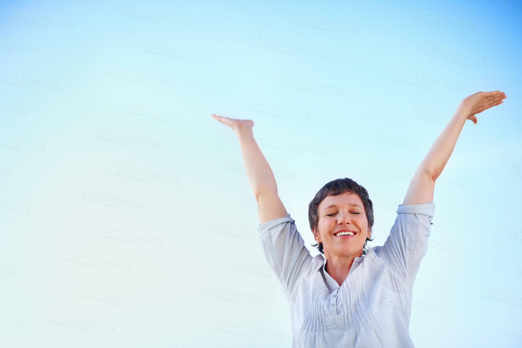 Buy stock photo Low angle view of playful mature woman enjoying freedom against sky with hands outstretched