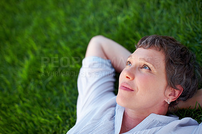 Buy stock photo Closeup of thoughtful mature woman relaxing while lying on grass