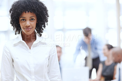 Buy stock photo A young african woman standing in the office with her colleagues in the background