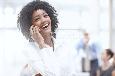 Buy stock photo An african woman laughing on her cellphone in the office with her colleagues behind her