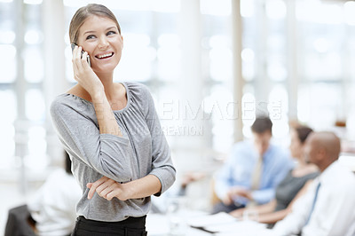 Buy stock photo An attractive woman using her mobile in the office with her colleagues in the background